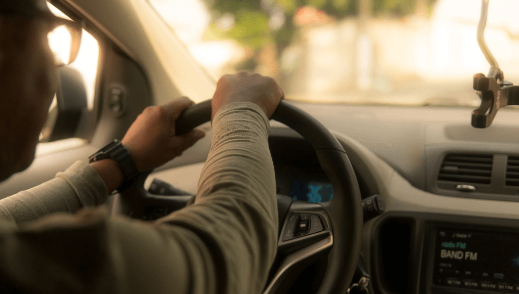 A driver holds a steering wheel while inside a car. Concept image of complimentary loaner car service of Bob Automotive.